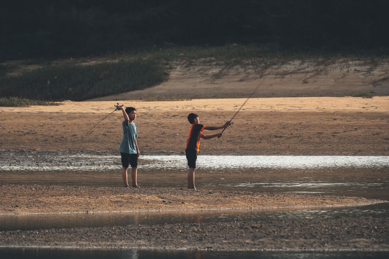 The Art of Drawing Readers In: Your attractive post title goes here Two boys fishing by a riverbank at sunset, enjoying outdoor adventure.